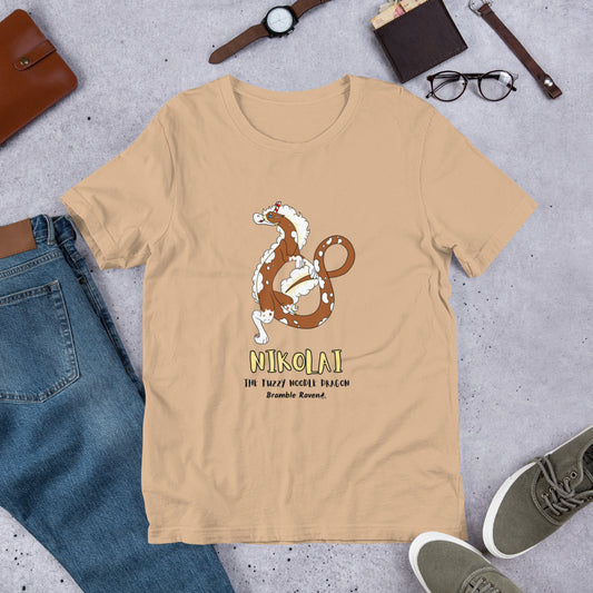 Nikolai the Fuzzy Noodle Dragon on a tan unisex t-shirt. Shown surrounded by pants, shoes, glasses, a watch, and wallet.