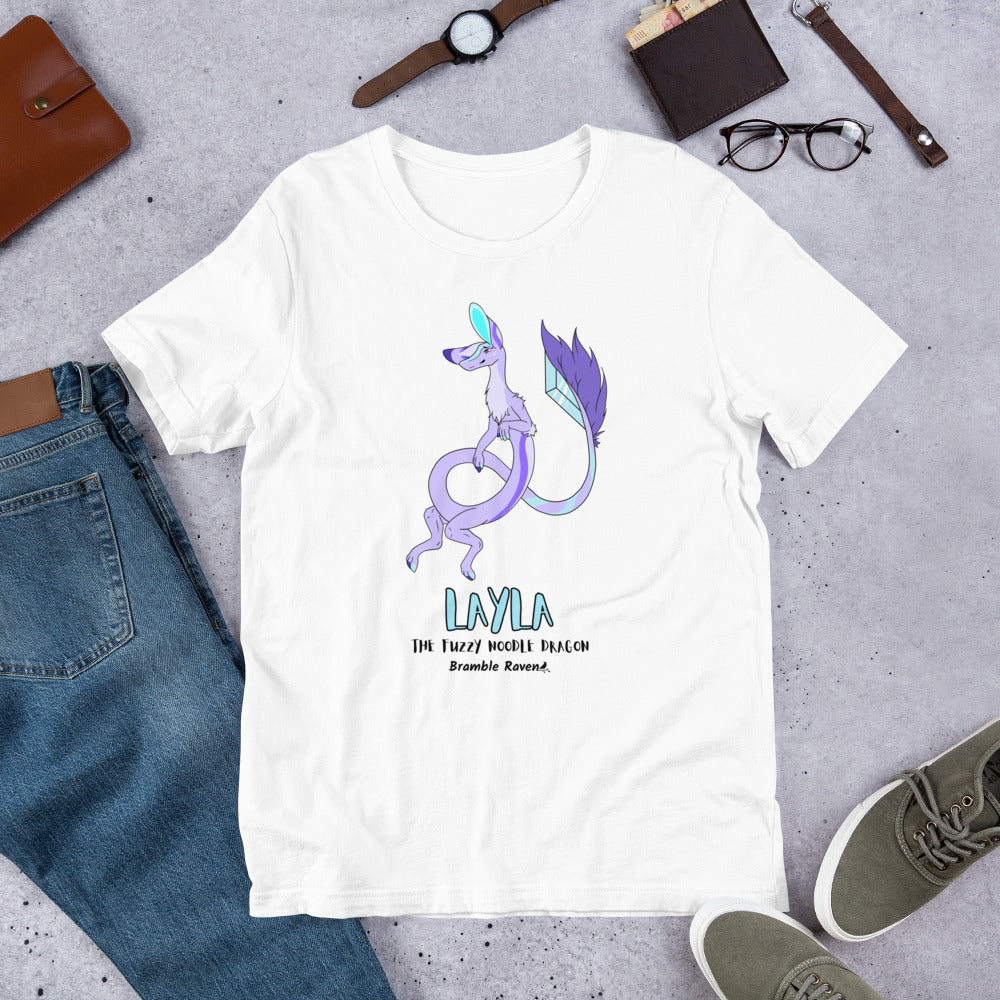 Layla the Fuzzy Noodle Dragon on a white unisex t-shirt. Shown surrounded by pants, shoes, glasses, a watch, and wallet.