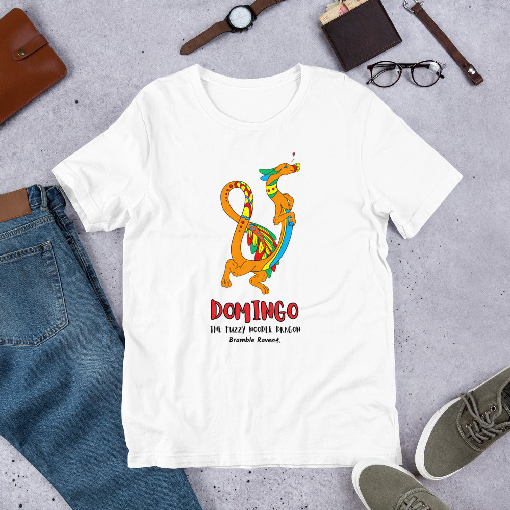 Domingo the Fuzzy Noodle Dragon on a white unisex t-shirt. Shown surrounded by pants, shoes, glasses, a watch, and wallet.