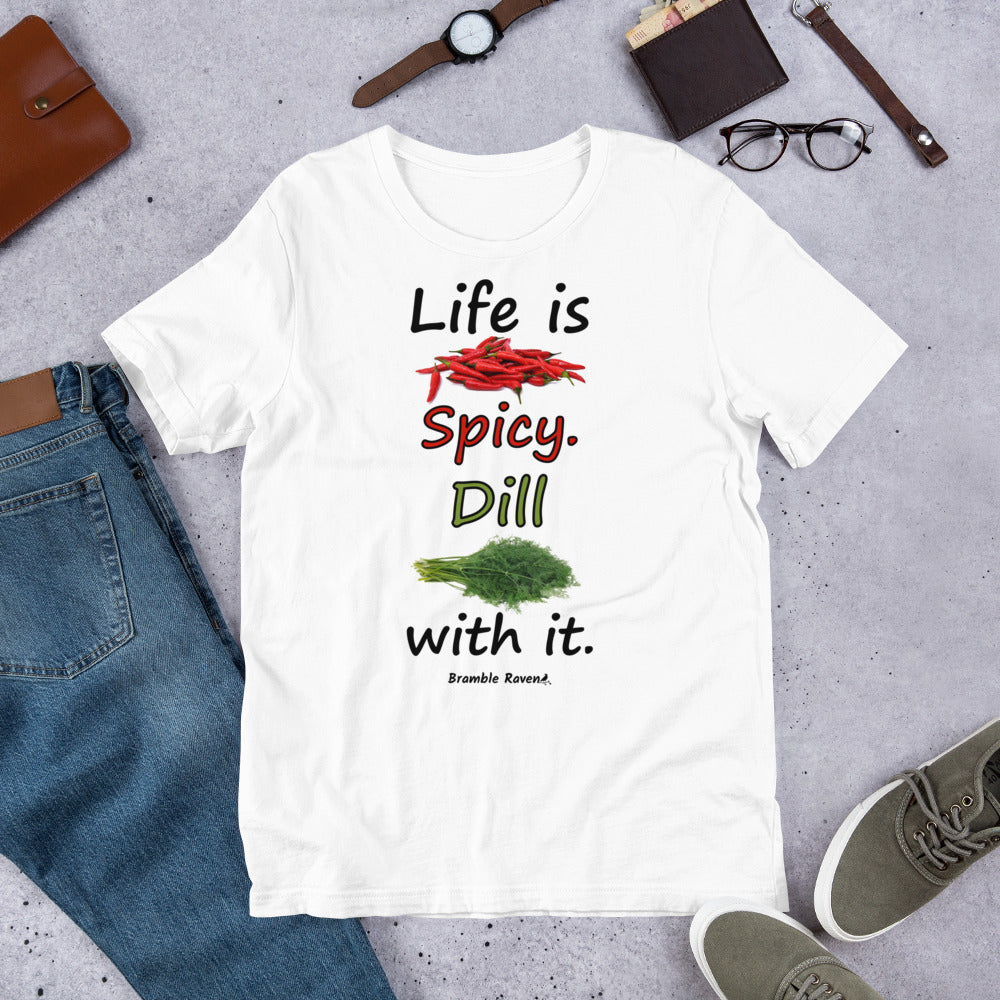 White colored unisex t-shirt. Features text: Life is Spicy. Dill with it. Graphic of chili peppers and dill weed. Made of preshrunk cotton with side seams. Shown on floor by pants, shoes, wallet and glasses.