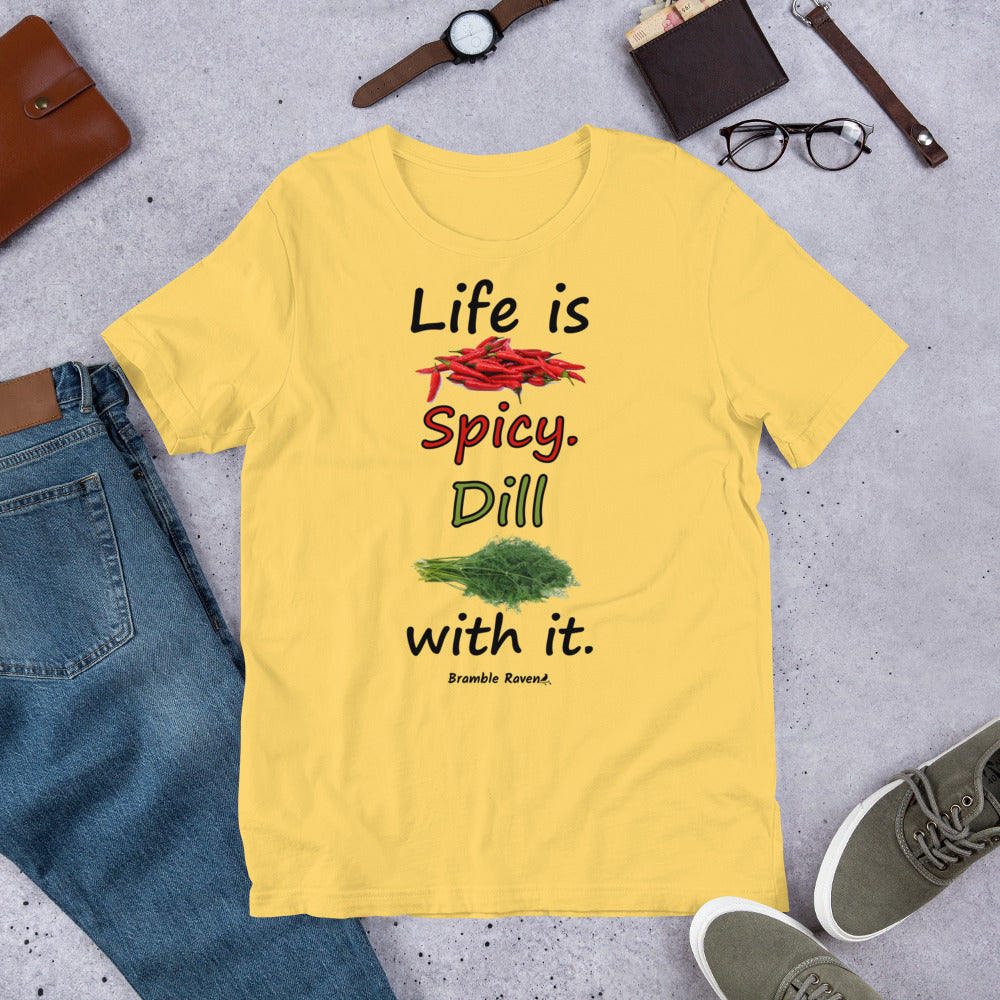 Yellow colored unisex t-shirt. Features text: Life is Spicy. Dill with it. Graphic of chili peppers and dill weed. Made of preshrunk cotton with side seams. Shown on floor by pants, shoes, wallet and glasses.