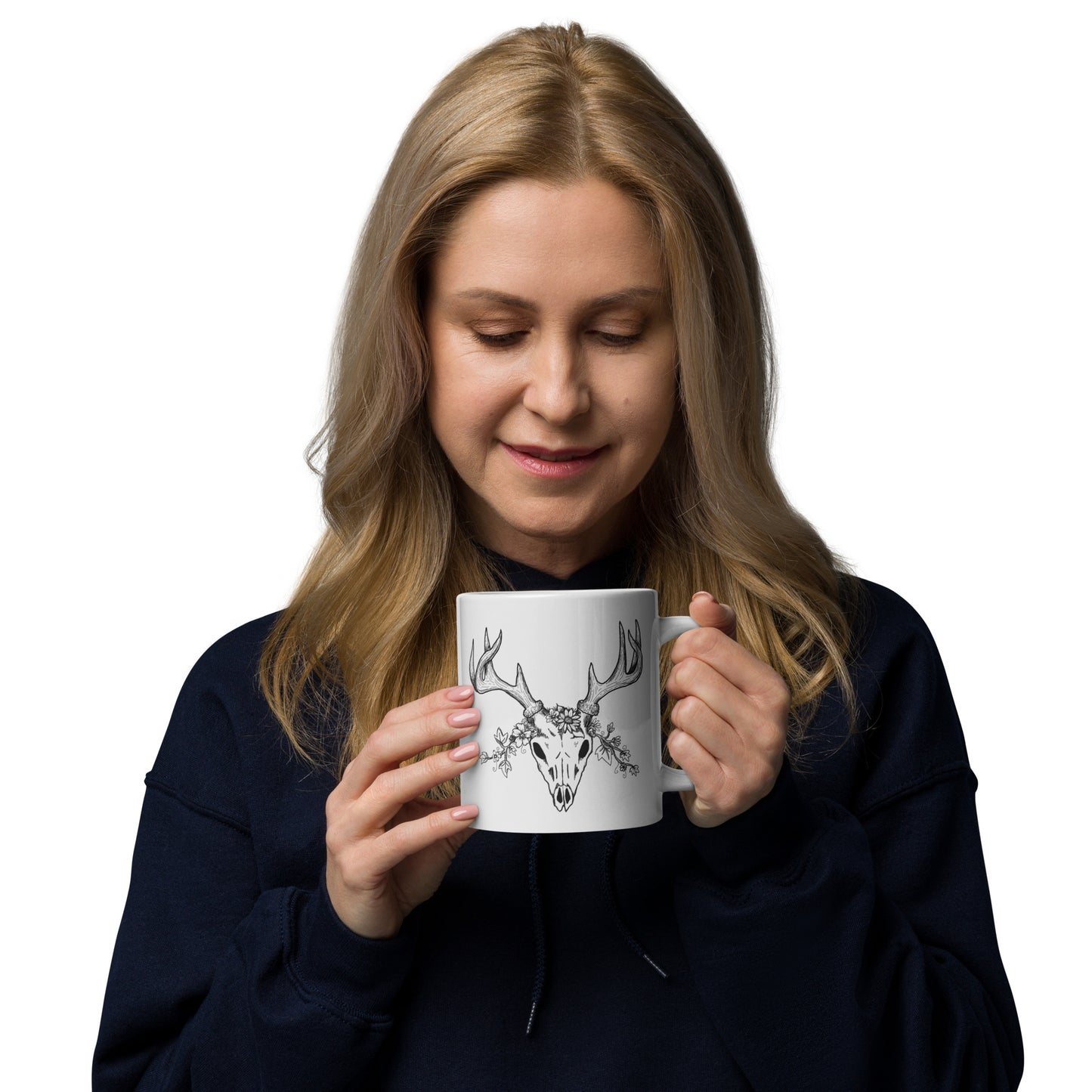 20 ounce white ceramic mug. Features hand-illustrated deer skull wreathed in flowers on one side, and text wildy beautiful, beautifully wild on the other side. Shown in female model's hands.