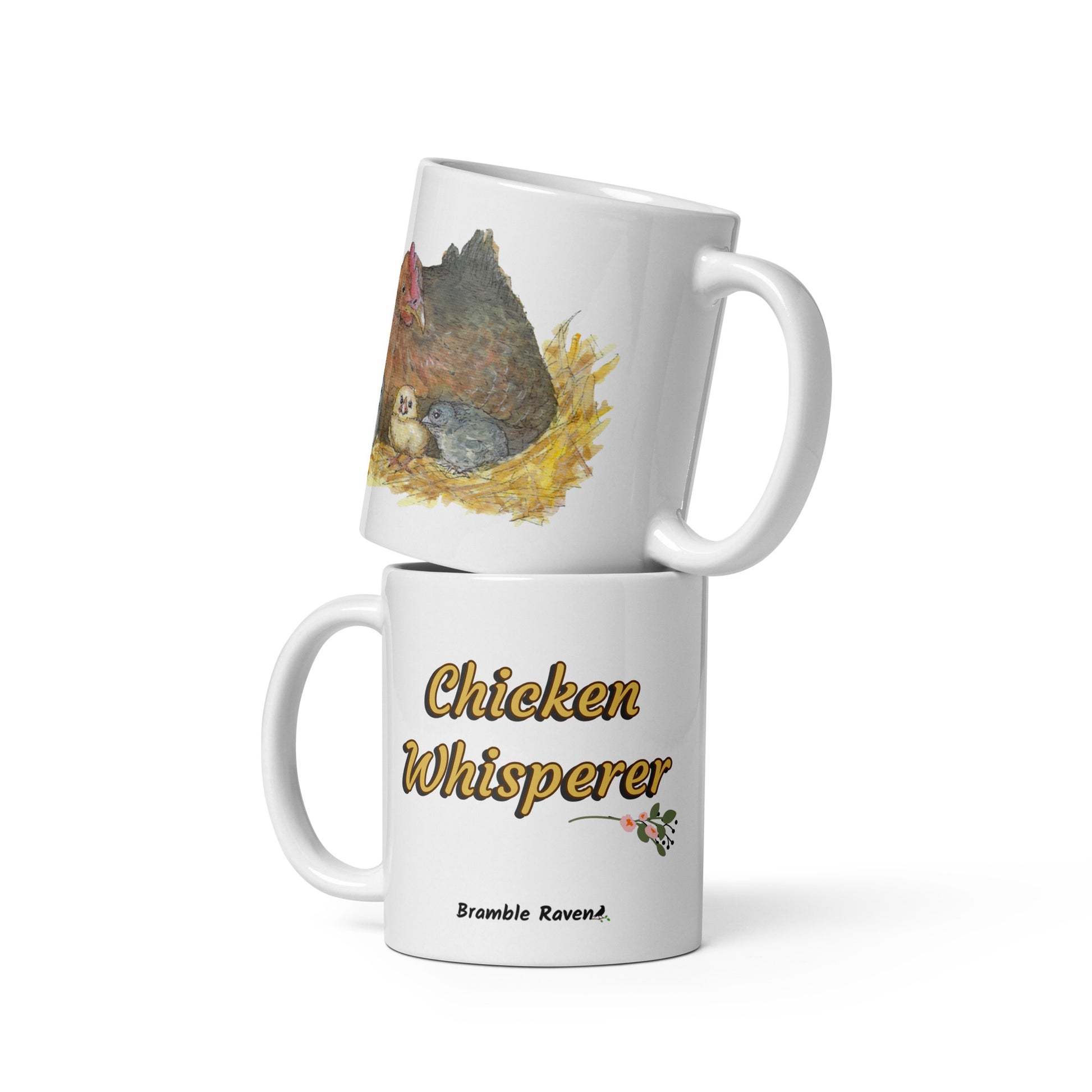 11 ounce white ceramic chicken whisperer mug. Features print of watercolor mother hen and chicks on one side and chicken whisperer text on the other. Dishwasher and microwave safe. Image shows two mugs stacked.