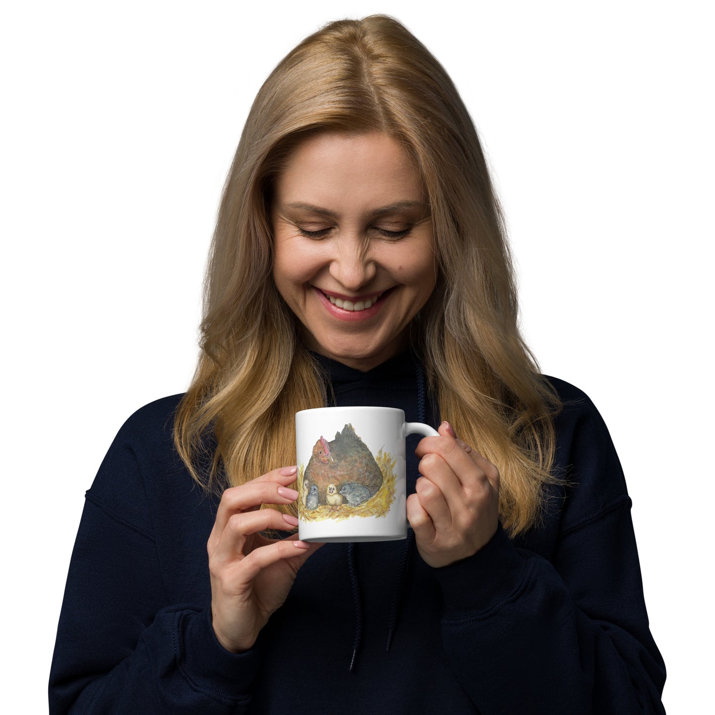 11 ounce white ceramic chicken whisperer mug. Features print of watercolor mother hen and chicks on one side and chicken whisperer text on the other. Dishwasher and microwave safe. Shown in smiling woman's hands.