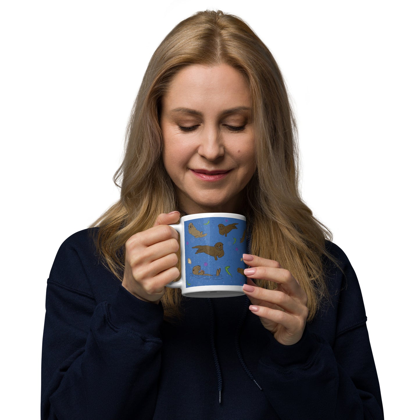 11 ounce white ceramic mug with sea otters on an ocean blue background. Mug is microwave and dishwasher safe. Shown in female model's hands.