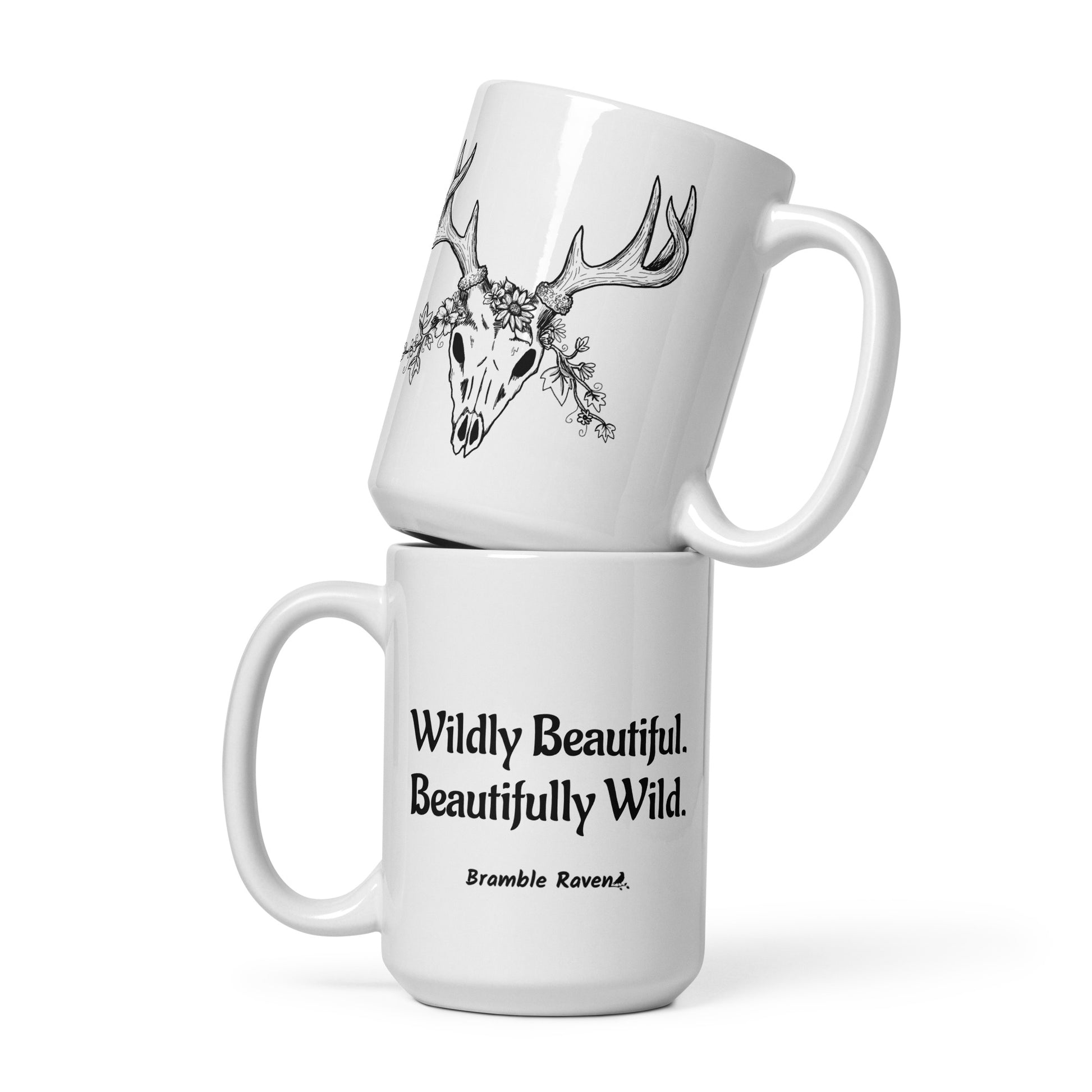 15 ounce white ceramic mug. Features hand-illustrated deer skull wreathed in flowers on one side, and text wildy beautiful, beautifully wild on the other side.