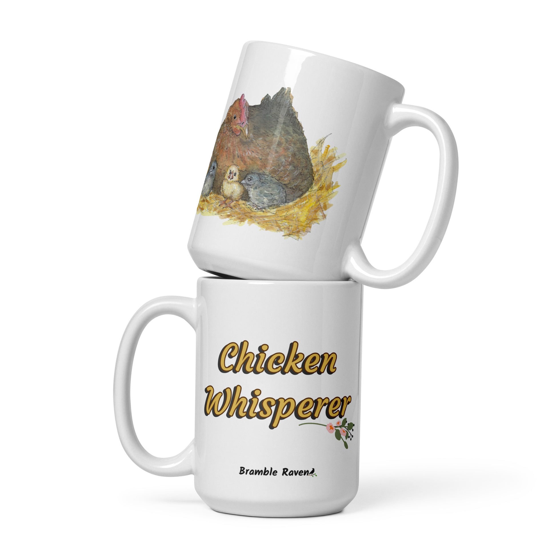 15 ounce white ceramic chicken whisperer mug. Features print of watercolor mother hen and chicks on one side and chicken whisperer text on the other. Dishwasher and microwave safe. Image shows two mugs stacked.