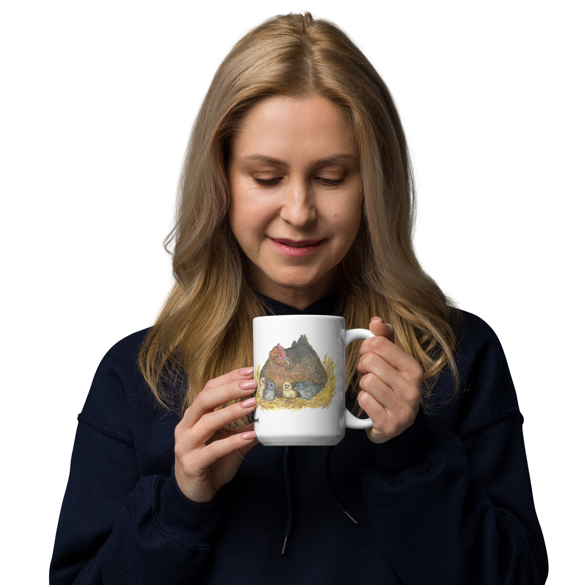 15 ounce white ceramic mug. Features double-sided print of a watercolor mother hen and chicks. Dishwasher and microwave safe. Shown in female model's hands.