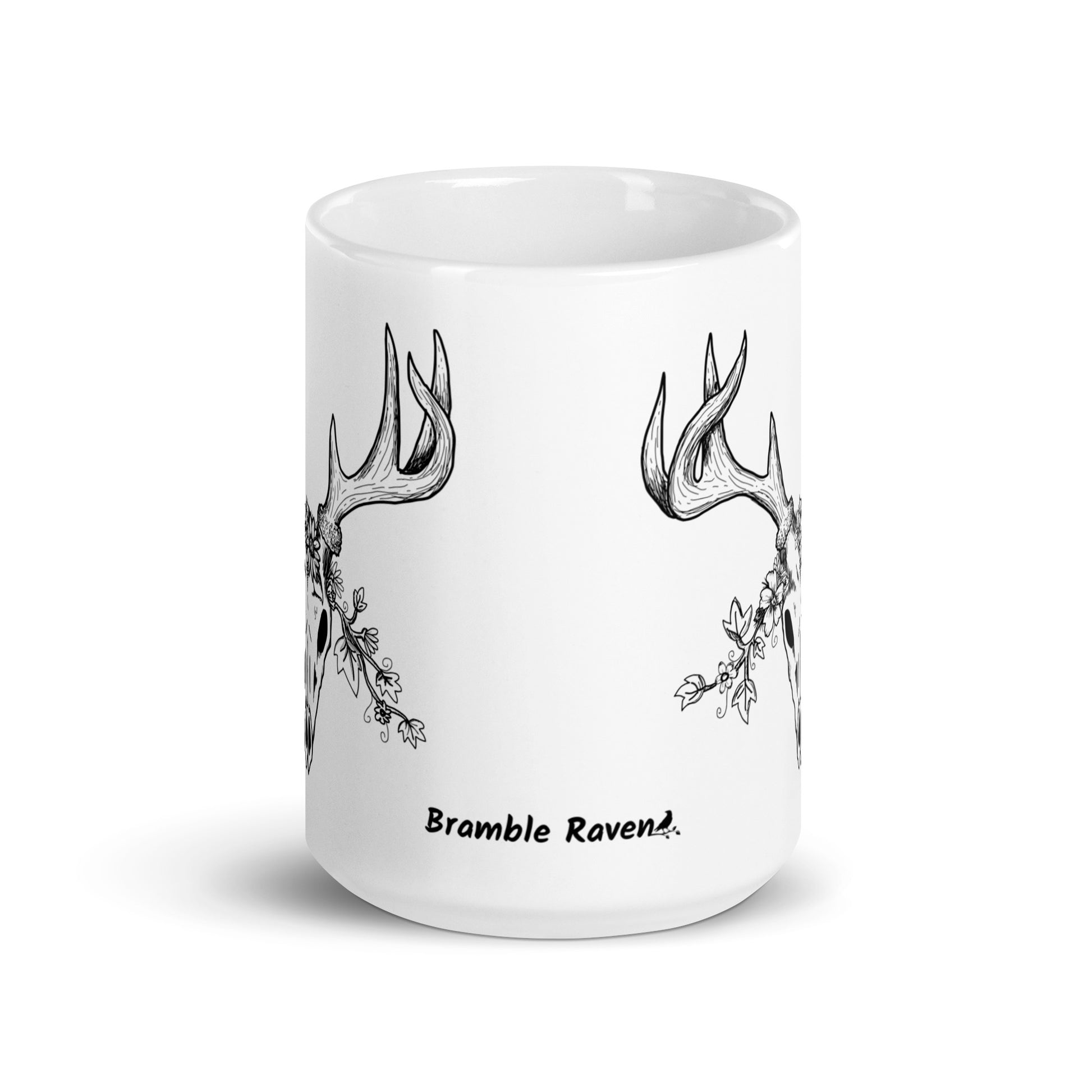 15 oz white ceramic mug. Features a double-sided hand illustrated image of a deer skull wreathed in flowers. Front view shows Bramble Raven logo.