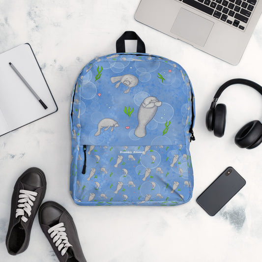 Medium-sized backpack featuring manatees, seashells, seaweed and bubbles on a blue background. Made with water resistant polyester, ergonomic straps, and comfort mesh back. Has a compartment that can hold a 15 inch laptop. Has a hidden zipper pocket on the back.