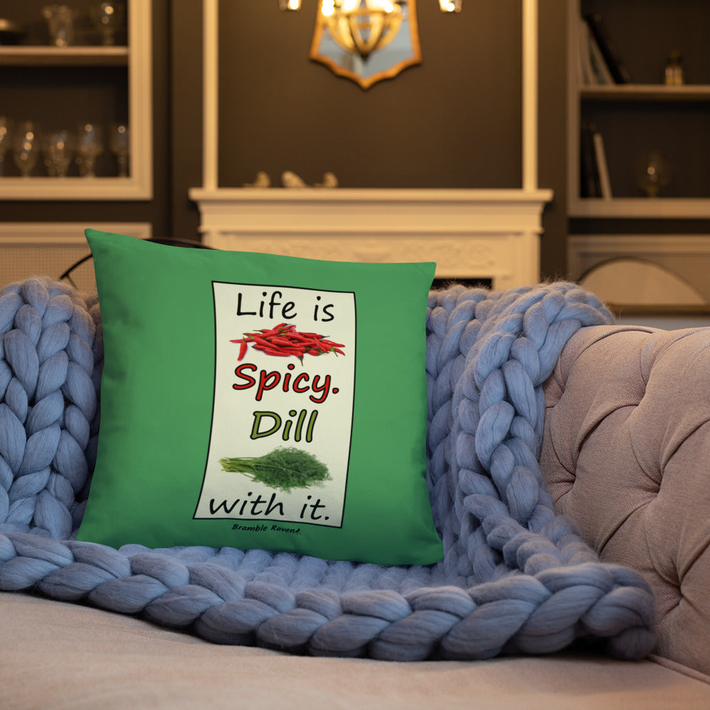 Life is spicy. Dill with it. Phrase with images of chili peppers and dill weed. Rectangular frame for saying on green background. 18 by 18 inch accent pillow. Double sided image. Shown on a blue knitted blanket on a tan couch.