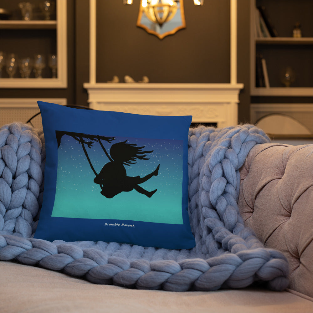 Original Swing Free design of a girl's silhouette in a tree swing against the backdrop of a blue starry sky. Rectangular image on front of pillow with blue background fabric. Pillow has design on both sides. 18 by 18 inch accent pillow. Shown on blue knitted blanket on tan sofa.