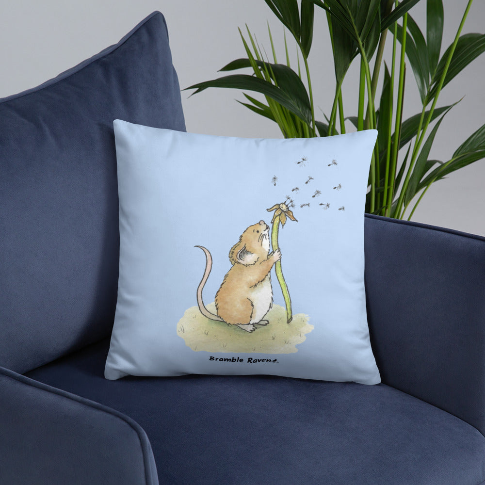 Original Dandelion Wish design of cute watercolor mouse blowing dandelion seeds on a light blue background. Double-sided image on 18 by 18 inch pillow. Shown on blue couch.