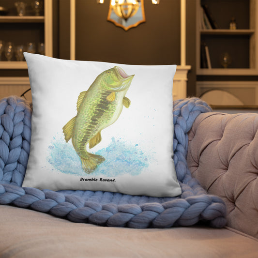 22 by 22 inch accent pillow. Features a watercolor painting of a largemouth bass leaping out of the water. Double sided design. Shown on a blue knitted blanket on a tan sofa.