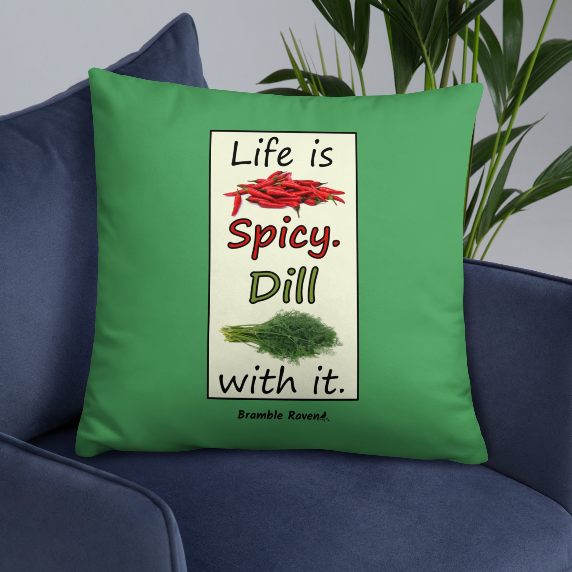 Life is spicy. Dill with it. Phrase with images of chili peppers and dill weed. Rectangular frame for saying on green background. 22 by 22 inch accent pillow. Double sided image. Shown on a blue couch.