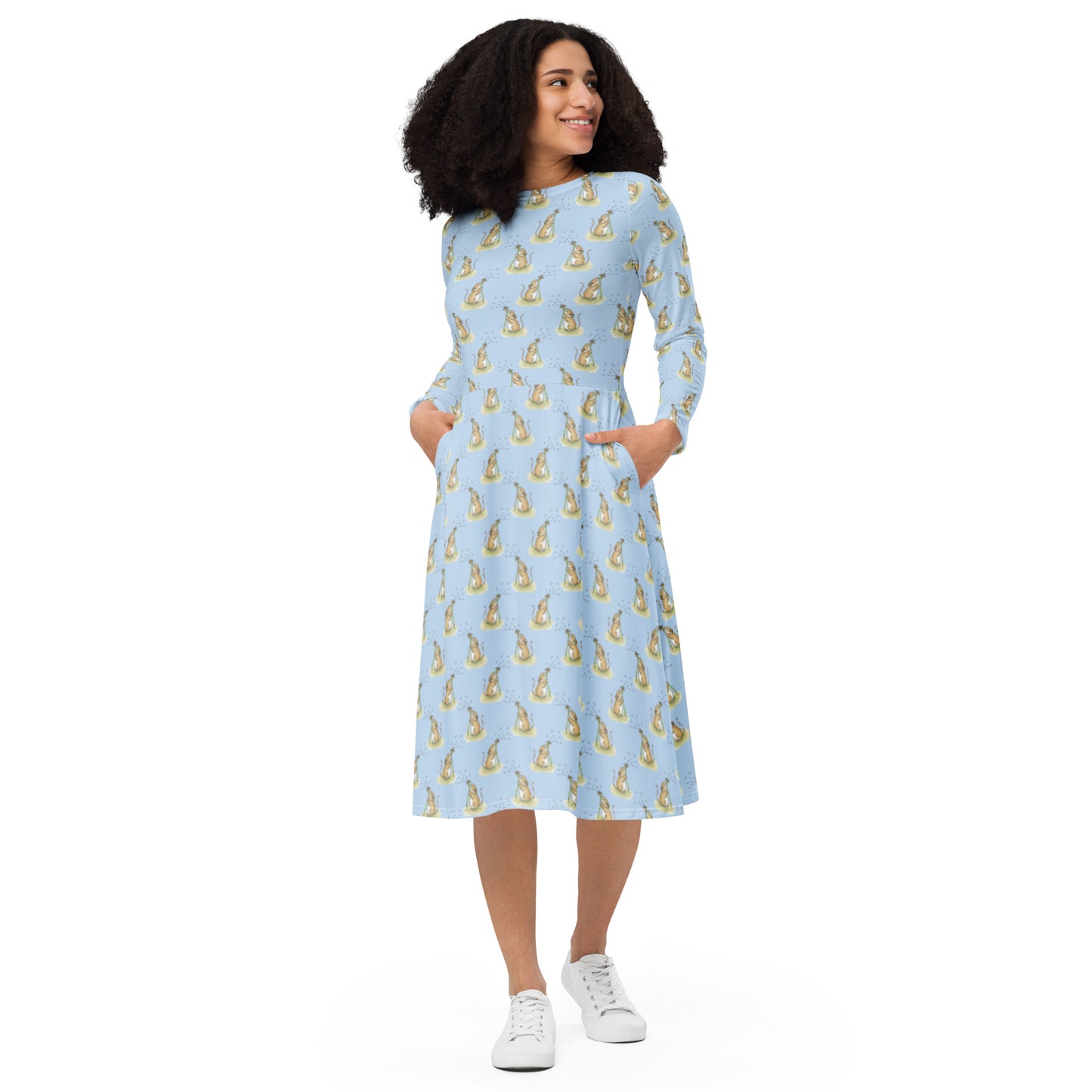Dandelion Wish patterned long sleeve midi dress. Features patterned design of a mouse making a wish on a dandelion fluff against a light blue background. Dress has boat neckline, fitted waist, flared bottom, and side pockets. Front view of female model with hands in her pockets.