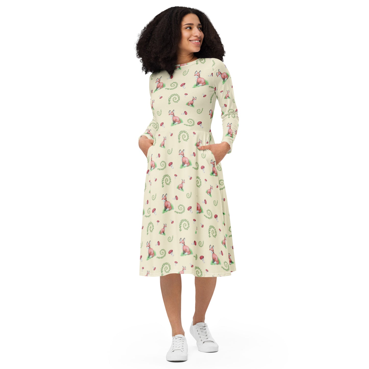 Fox pattern long sleeve midi dress with side pockets, fitted waist, and flared bottom. Foxes, ferns, and mushrooms are patterned on the apricot white fabric. Soft and comfortable. Front view on female model.