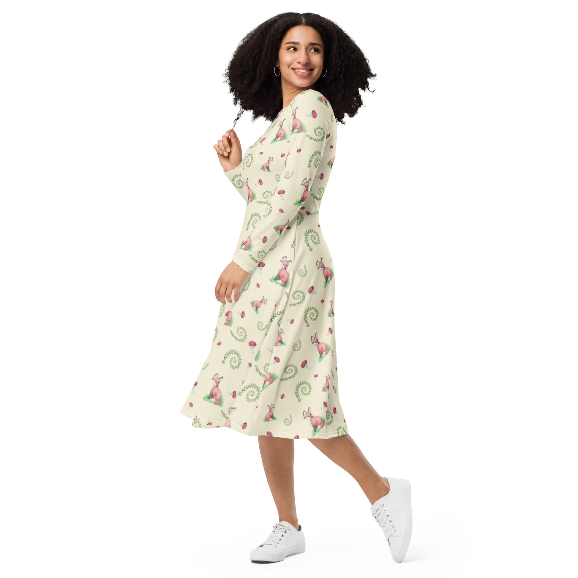 Fox pattern long sleeve midi dress with side pockets, fitted waist, and flared bottom. Foxes, ferns, and mushrooms are patterned on the apricot white fabric. Soft and comfortable. Shown on female model facing left.