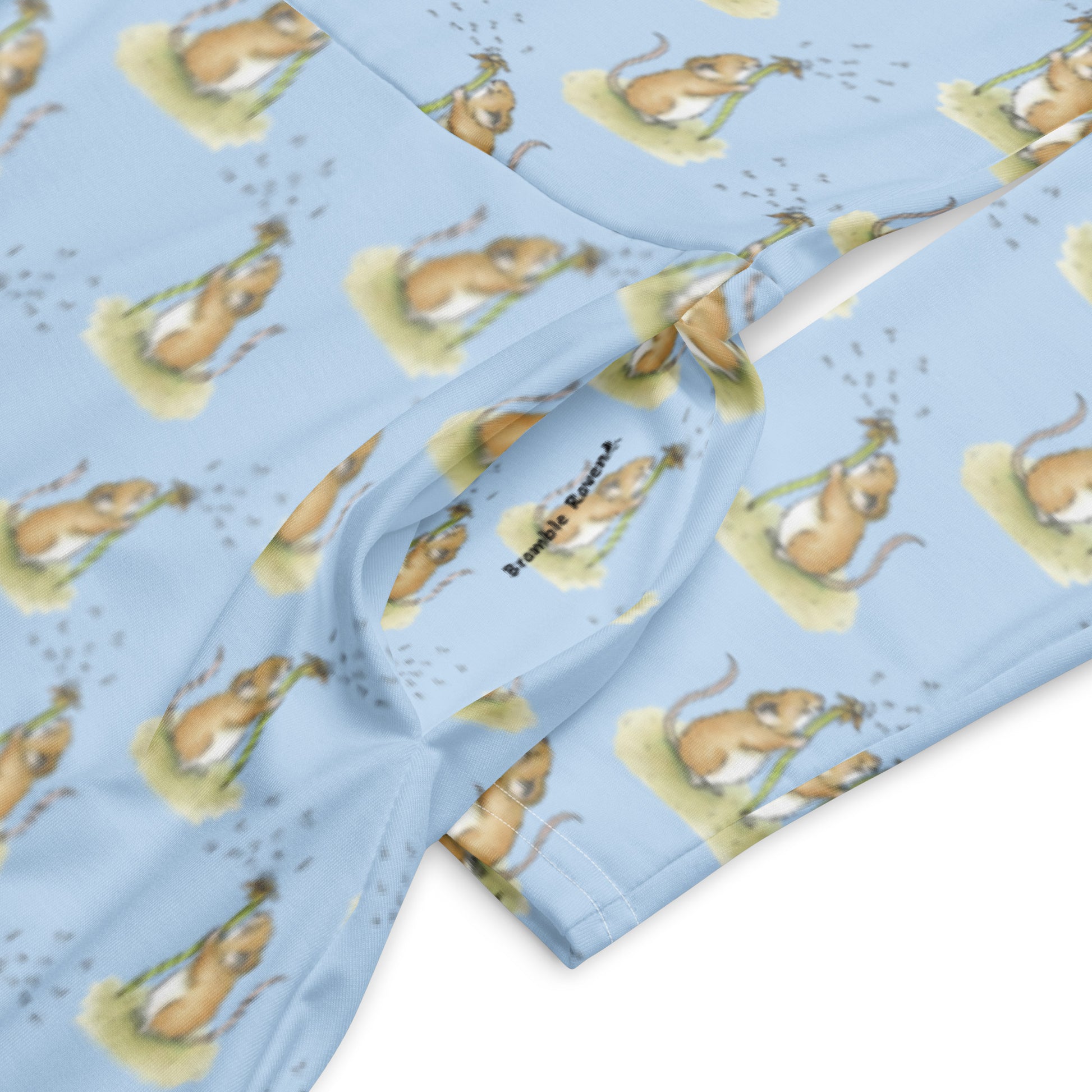 Dandelion Wish patterned long sleeve midi dress. Features patterned design of a mouse making a wish on a dandelion fluff against a light blue background. Dress has boat neckline, fitted waist, flared bottom, and side pockets. Detail image of pocket with Bramble Raven logo.