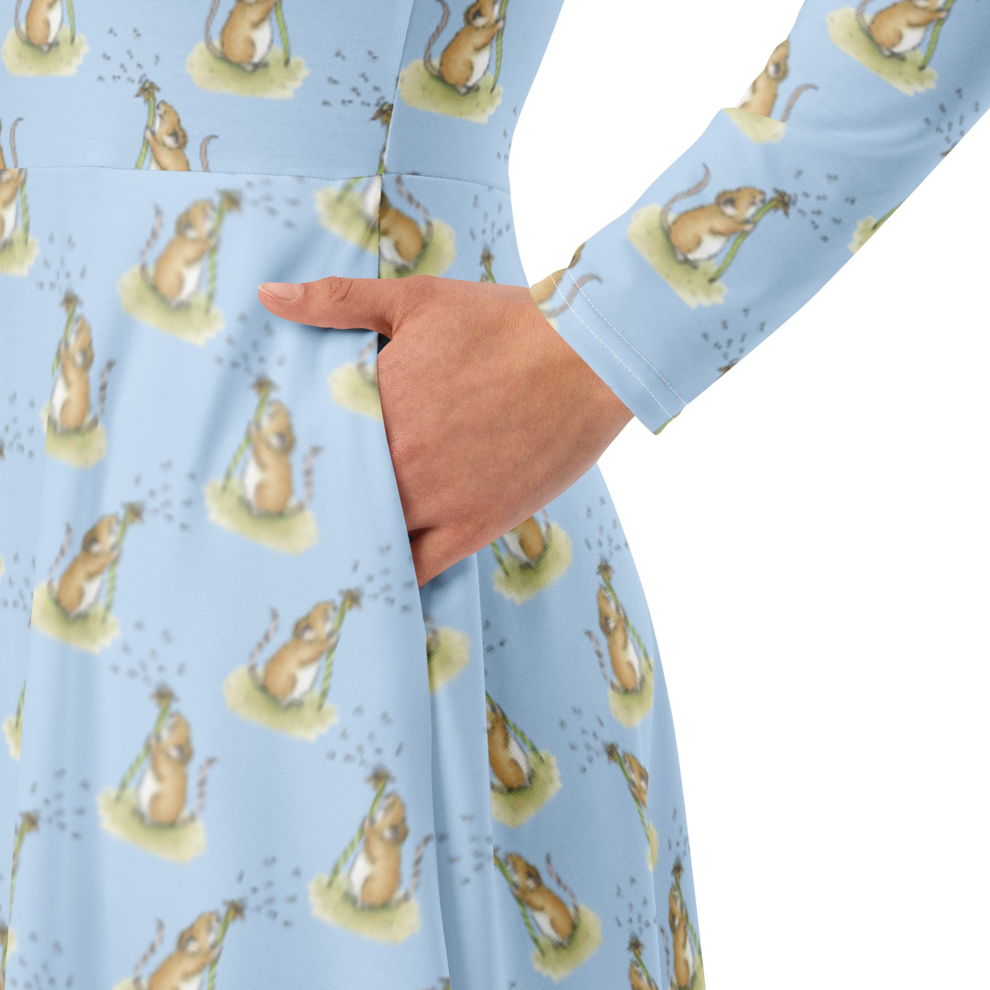 Dandelion Wish patterned long sleeve midi dress. Features patterned design of a mouse making a wish on a dandelion fluff against a light blue background. Dress has boat neckline, fitted waist, flared bottom, and side pockets. Detail image showing model's hand in side pocket.