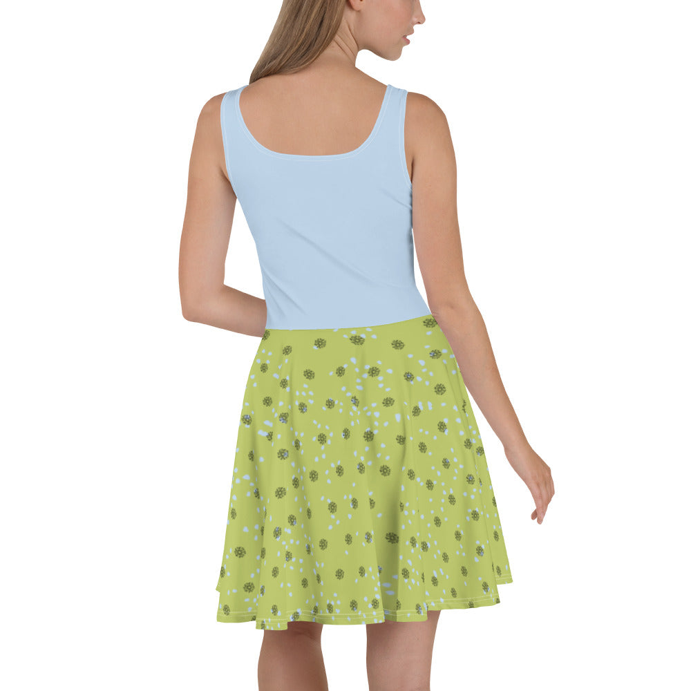 Sleeveless skater dress featuring Dandelion Wish design of a mouse making a wish on a dandelion fluff on a blue top. The mid-thigh length flared green skirt features flowers and dot details. Also has an elastic waistline. Back view on female model.