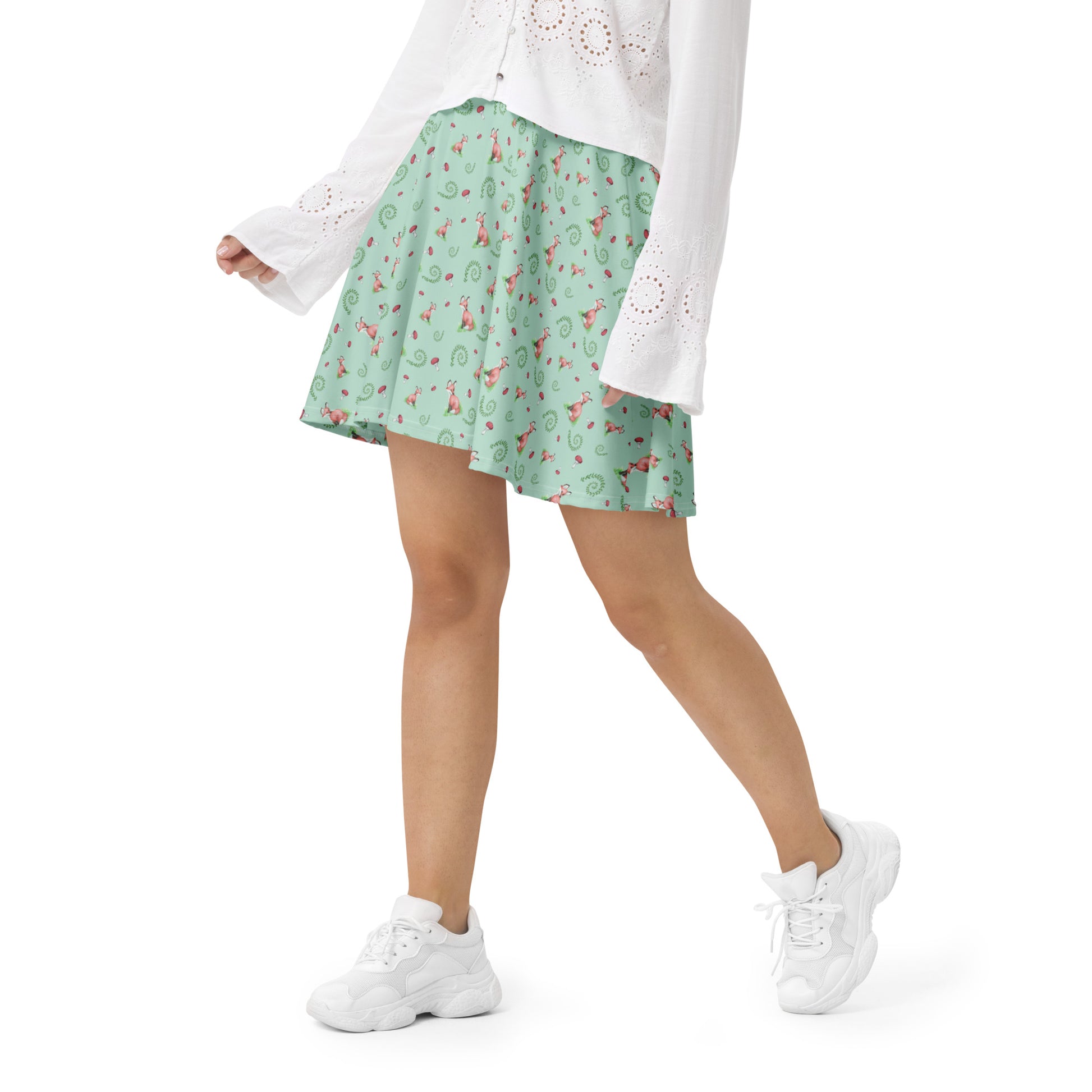 Forest Fox patterned skater skirt with mushrooms and ferns. Flared cut, mid-thigh length with elastic waist. Shown on female model with white sweater and shoes.