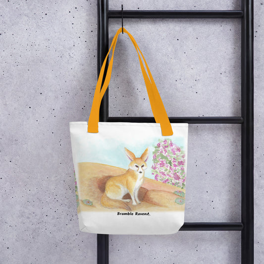 15 by 15 inch polyester tote bag. White bag with yellow handles. Features original watercolor painting of a fennec fox in the desert. Shown hanging on a black ladder.