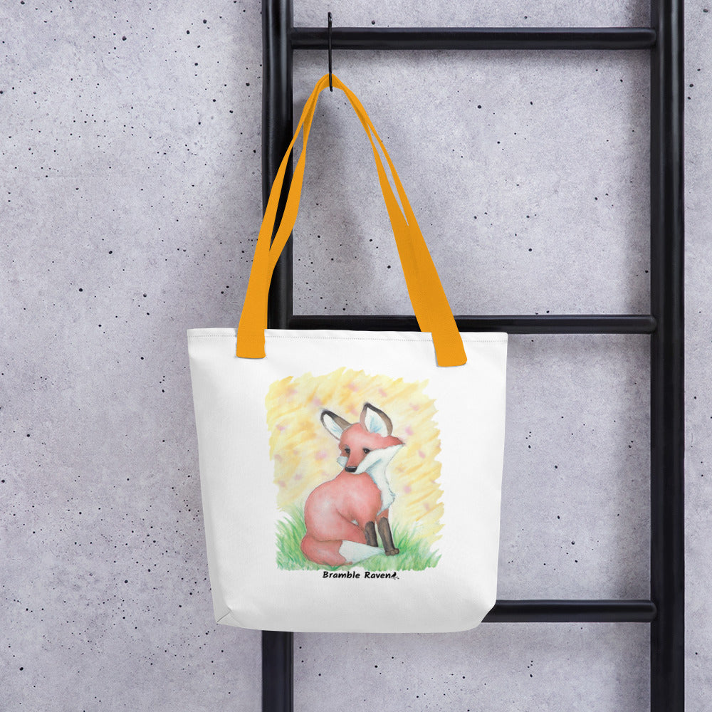 15 by 15 inch white polyester tote bag with yellow handles. Features original watercolor painting of a fox in the grass against a yellow background. Shown hanging on a black ladder.