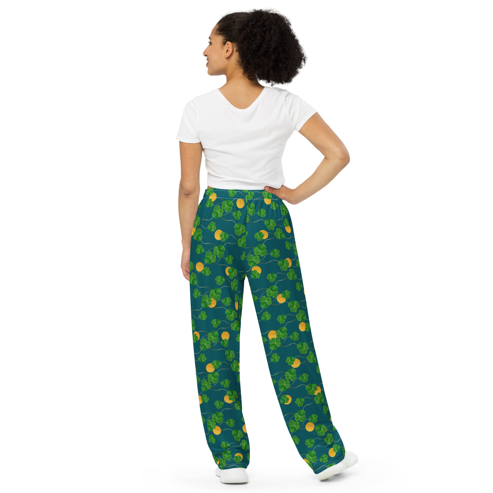 Unisex wide leg pants with side pockets, elastic waistband and drawstring.  Design features pattern of three-leaf clover and lucky gold coins on a blue-green background. Back view on female model.