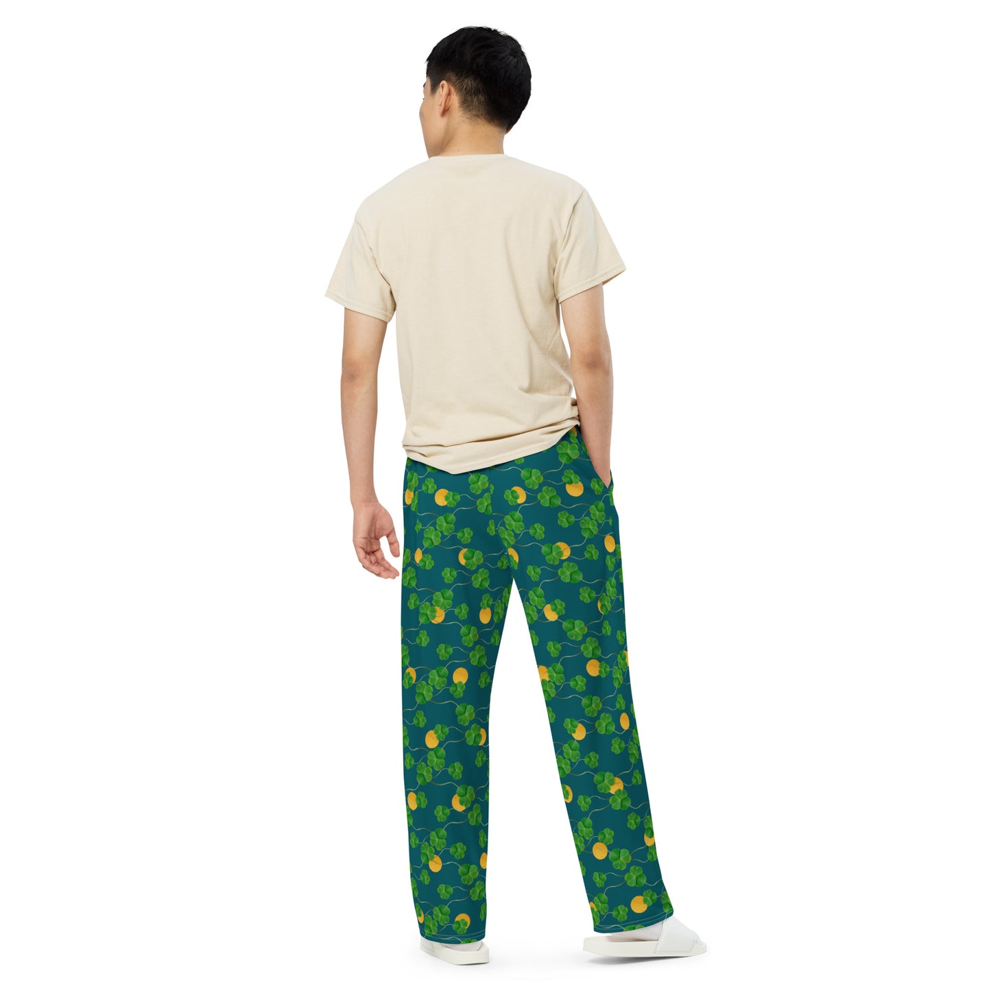 Unisex wide leg pants with side pockets, elastic waistband and drawstring.  Design features pattern of three-leaf clover and lucky gold coins on a blue-green background. Back view on male model.
