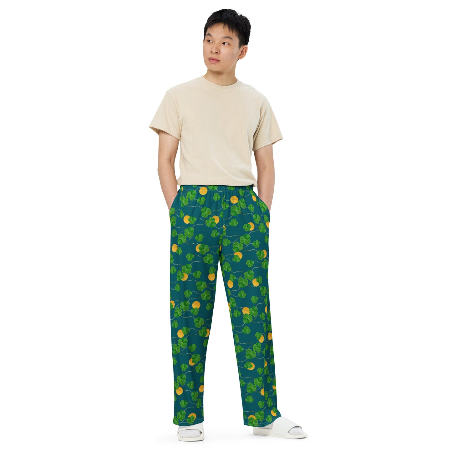 Unisex wide leg pants with side pockets, elastic waistband and drawstring.  Design features pattern of three-leaf clover and lucky gold coins on a blue-green background. Shown on male model.