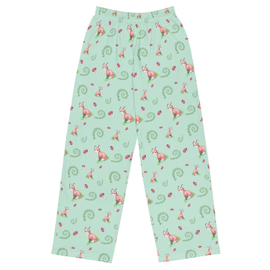 Unisex wide-leg pants with watercolor foxes, mushrooms, and ferns on a light green fabric. Has an elastic waistband, white draw cord, and side pockets. 