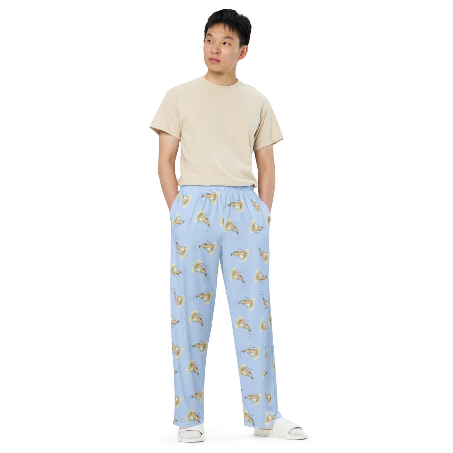 Unisex wide leg polyester pajama pants. Features dandelion wish patterned design on a light blue fabric. Has elastic waistband and white drawstring. Side pockets. Shown on male model.