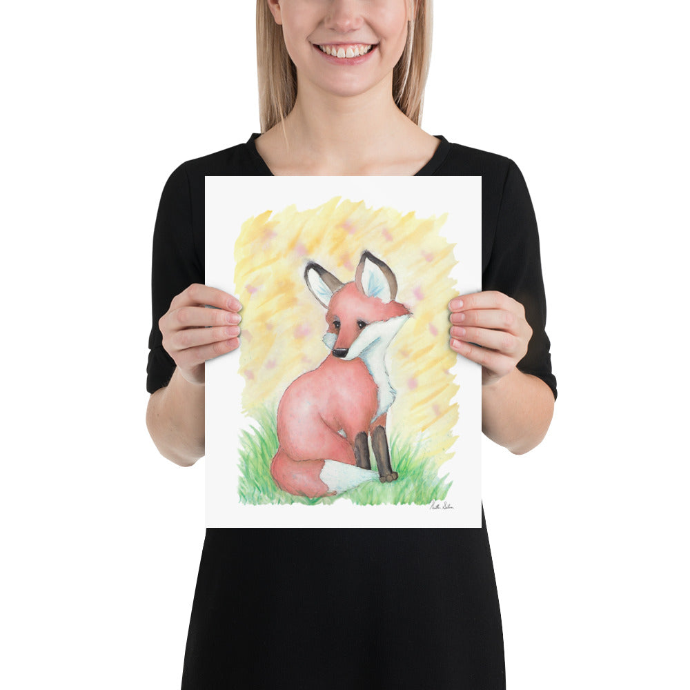 11x14 matte paper art print. Giclée quality printing. Design is a watercolor painting of a fox in the grass against a yellow background. Shown in the hands of a female model.