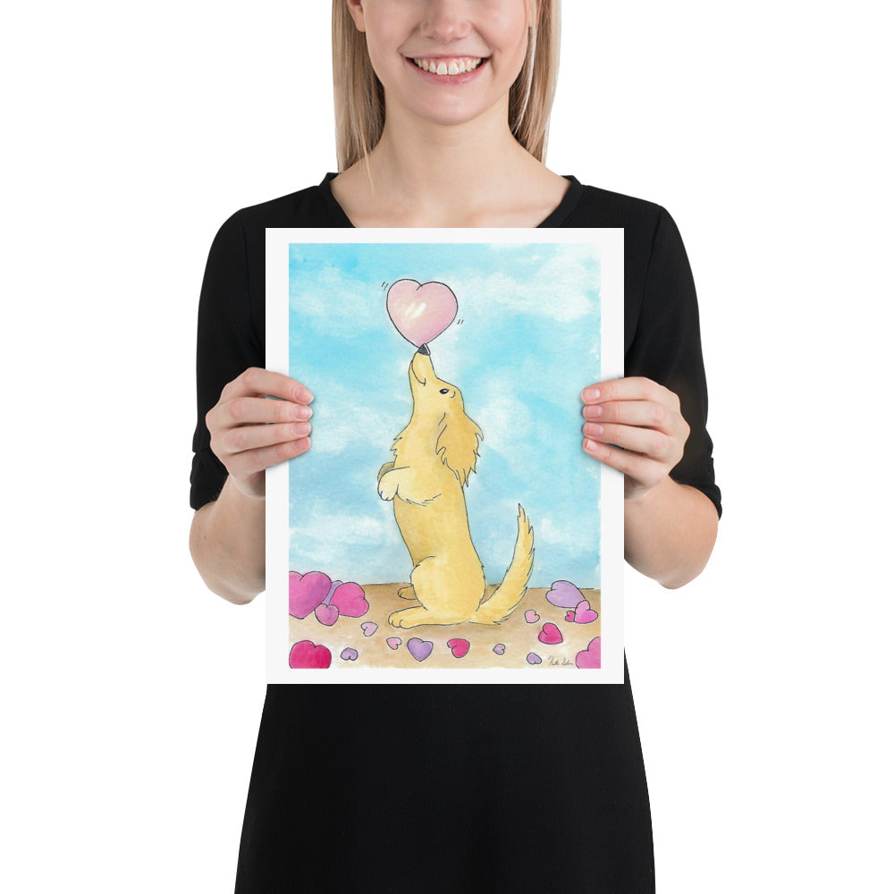 11 x 14 inch enhanced matte paper art print. Watercolor painting entitled Puppy love. Design shows a cute puppy balancing a heart on its nose, with hearts on the floor and a blue sky background. Shown being held in front of female model.