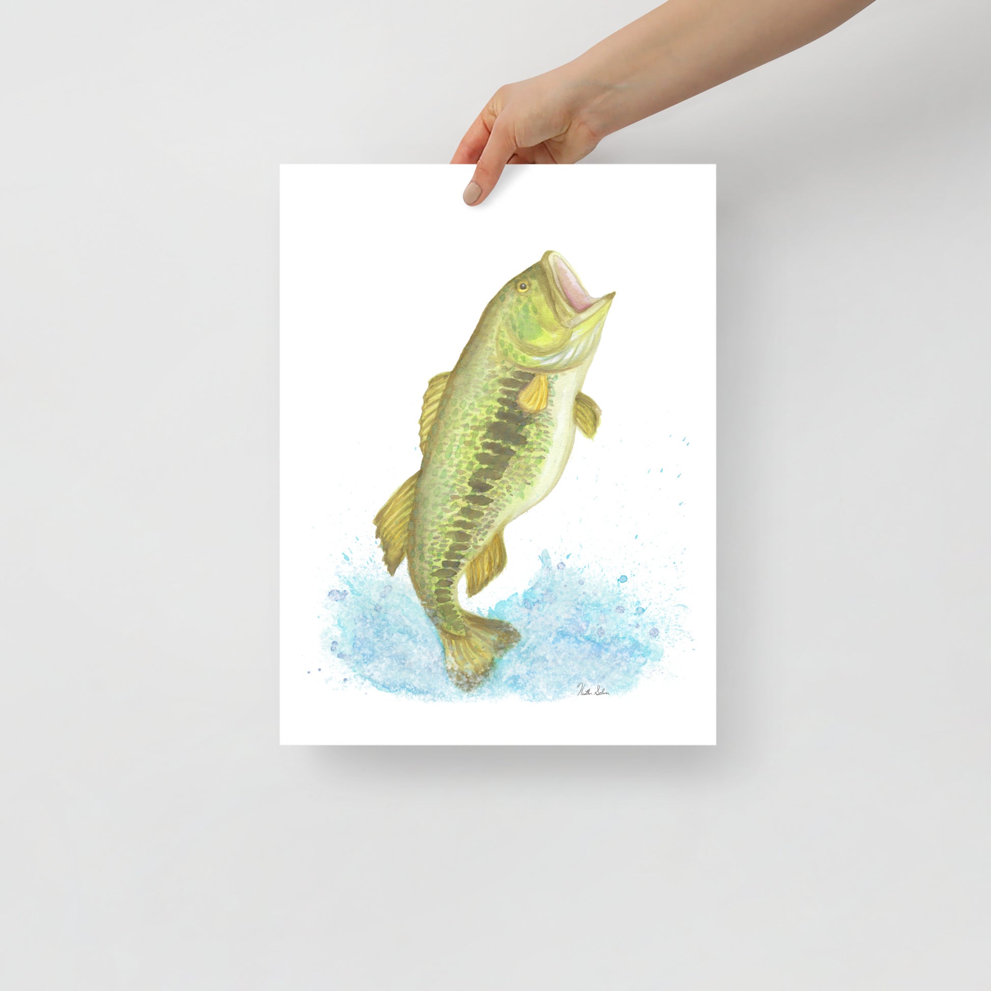 12 x 16 inch matte paper art print of an original watercolor painting of a largemouth bass leaping from the water. Shown being held by a model's hand.