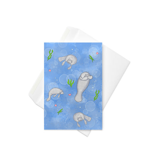 4 x 6 inch greeting card with white envelope. Inside is blank. Has four cute roly-poly manatees surrounded by seashells, seaweed, and bubbles on a blue background.