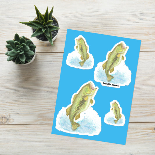 Glossy sticker sheet with four kiss cut stickers with white borders. Features a watercolor painting of a largemouth bass leaping out of the water. Four fish stickers facing different directions and different sizes on a single sheet. Shown on a table with potted plants.