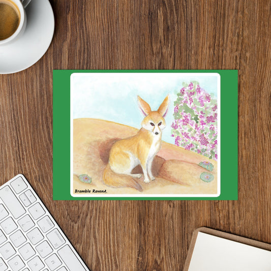 5.75 by 7 inch glossy sticker sheet with one rectangular kiss cut sticker with a white border. Features original watercolor painting of a fennec fox in the desert. Shown on a desktop.