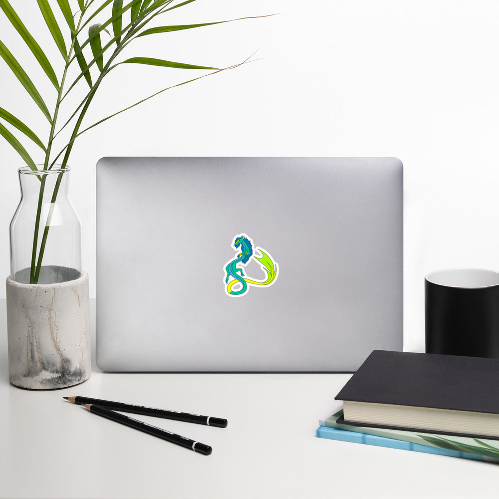 Mikori the Fuzzy Noodle Dragon. Original character design kiss-cut vinyl sticker with white border. 3 inches tall. Shown on a laptop.