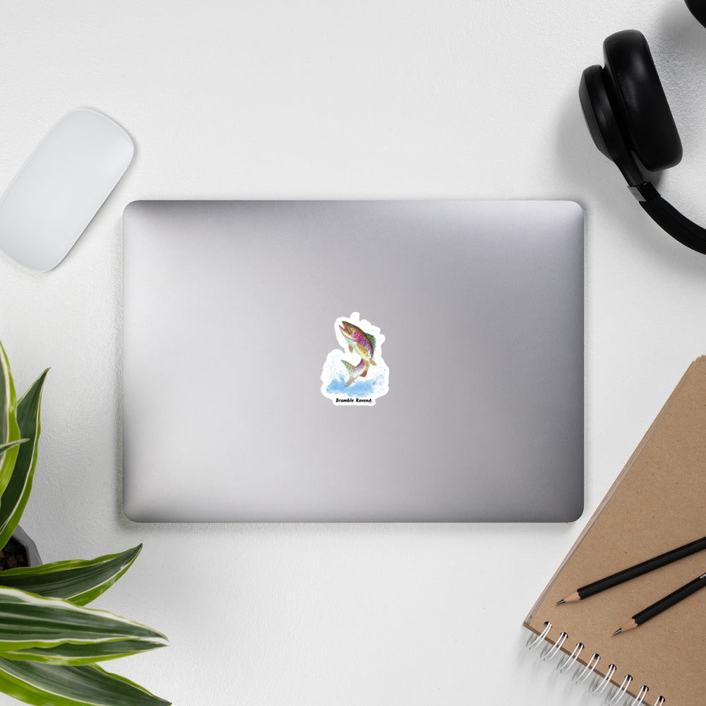 3 inch kiss-cut vinyl sticker with white border. Features original watercolor painting of a rainbow trout leaping from the water. Shown on a laptop.