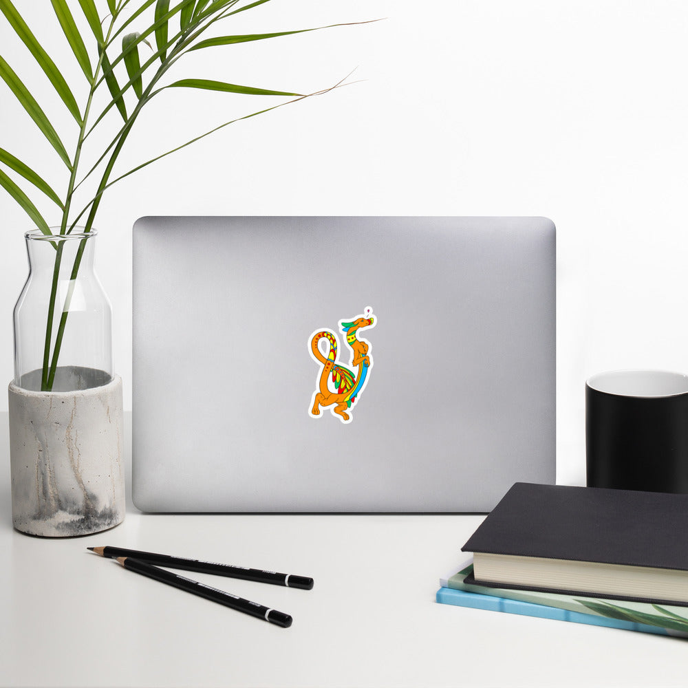 Domingo the Aztec Fuzzy Noodle Dragon. Original character design kiss-cut vinyl sticker with white border. 4 inches tall. Shown on a laptop.