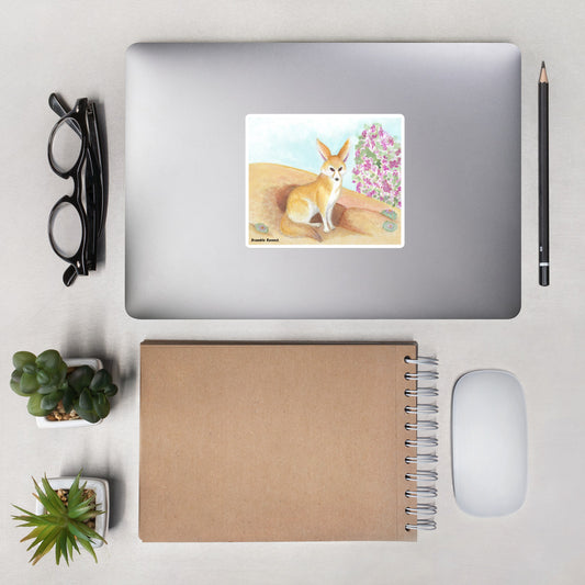 5.5 inch kiss-cut vinyl sticker with white border featuring an original watercolor painting of a fennec fox in the desert. Shown on a laptop.
