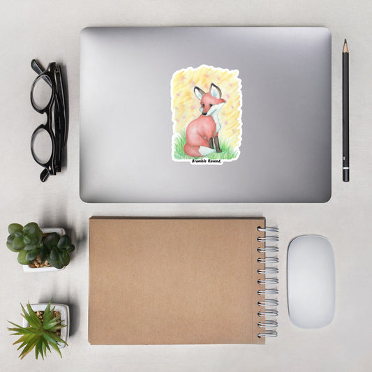 5.5 inch kiss cut vinyl sticker. Features original watercolor painting of fox in the grass against a yellow backdrop. Shown on a laptop.
