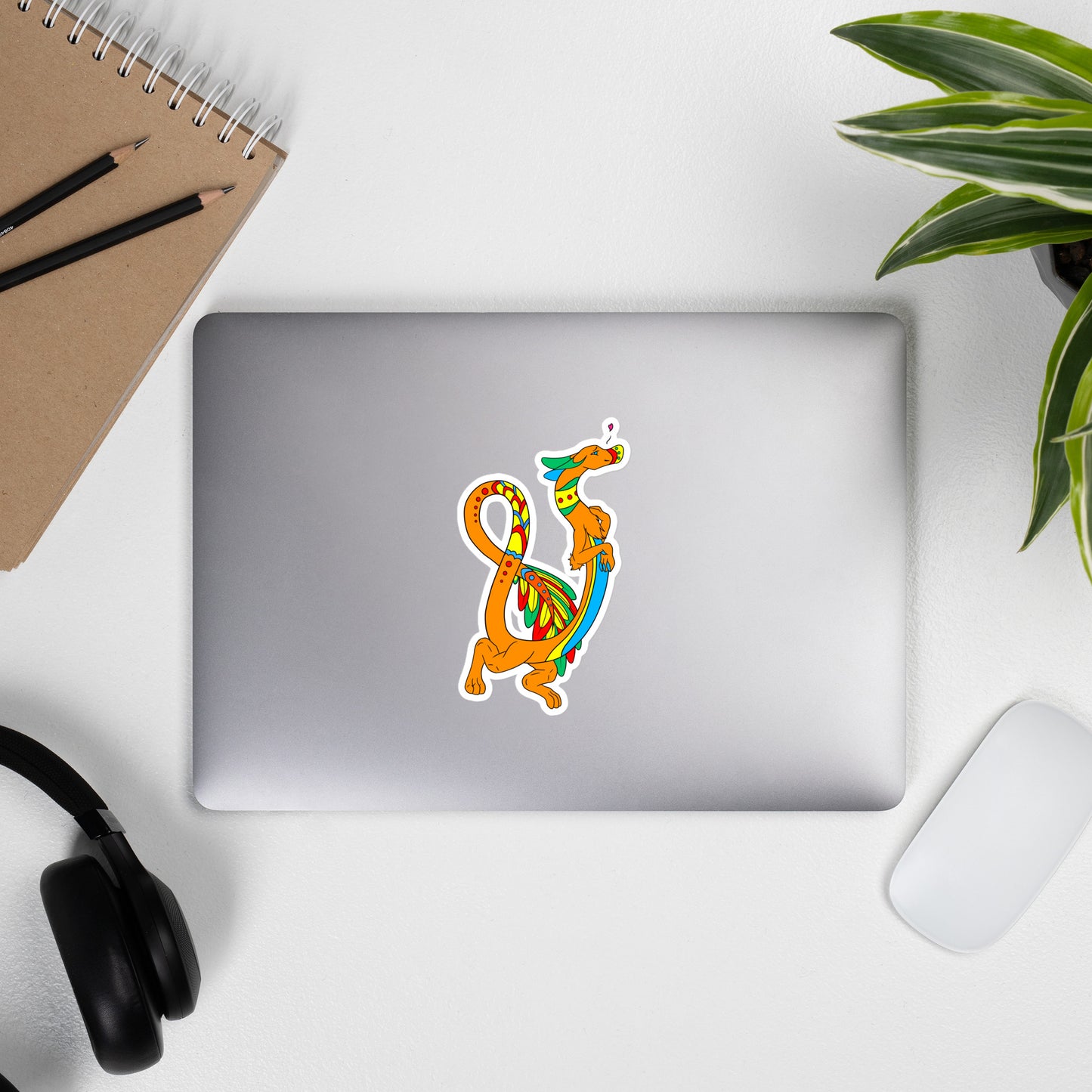 Domingo the Aztec Fuzzy Noodle Dragon. Original character design kiss-cut vinyl sticker with white border. 5.5 inches tall. Shown on a laptop.