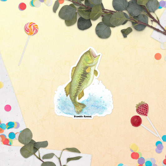 5.5 inch vinyl kiss-cut sticker with white border. Features original watercolor painting of a largemouth bass leaping from the water. Shown on table surrounded by candy and leaves.
