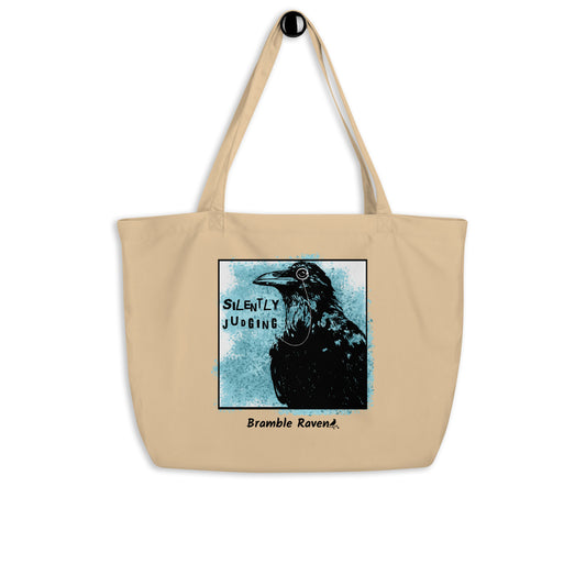 Original Silently Judging crow design with blue paint splatters. Silently Judging text. Black crow with monocle in square frame. Printed on large oyster-colored eco tote. 20 by 14 by 5 inches. 100% recycled cotton.