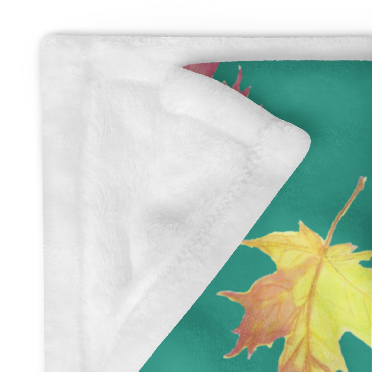 50 by 60 inch soft throw blanket featuring watercolor fall leaves patterned on a dark green background. Show with corner folded over to show white underside.