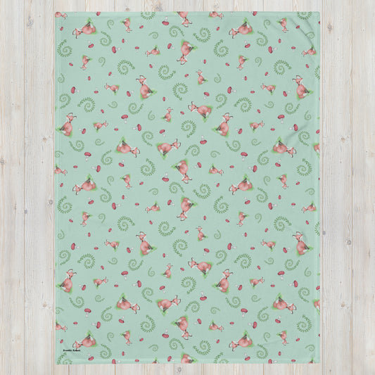 60 by 80 inch watercolor forest fox patterned blanket. Made of soft and fluffy polyester. Has foxes, mushrooms, and ferns on light green background. White underside. Machine-washable, hypoallergenic, and flame retardant. Shown on floor.