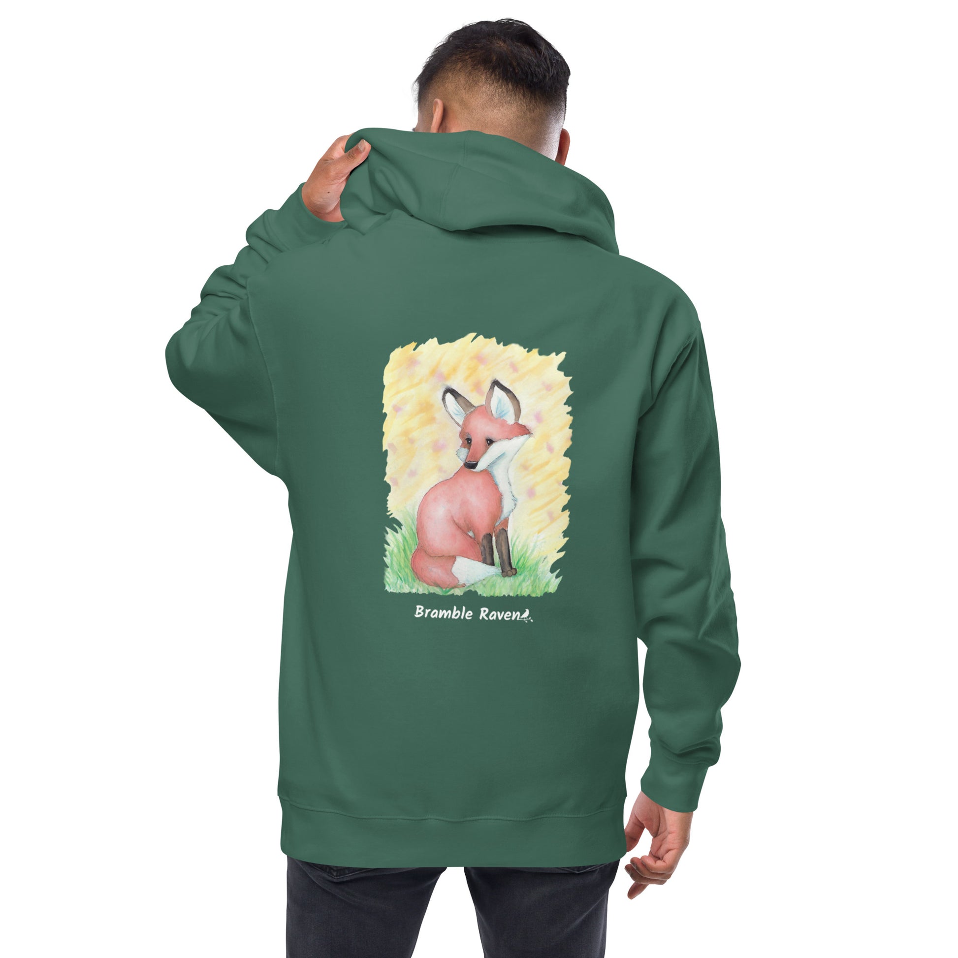 Unisex alpine green colored zip-up fleece-lined hoodie. Features original watercolor painting of a fox sitting in the grass on the back of the hoodie. Shown on male model.